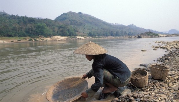 Laos, Mekong river, young woman panning for gold